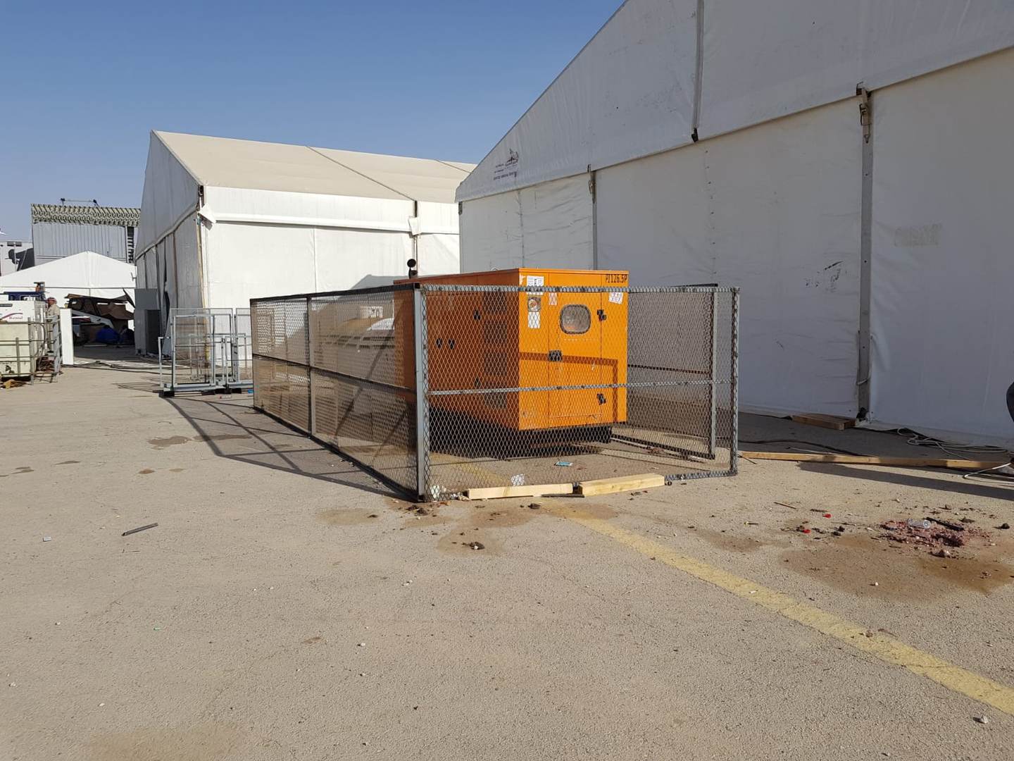 Generator secured in fenced enclosure between exhibition tents