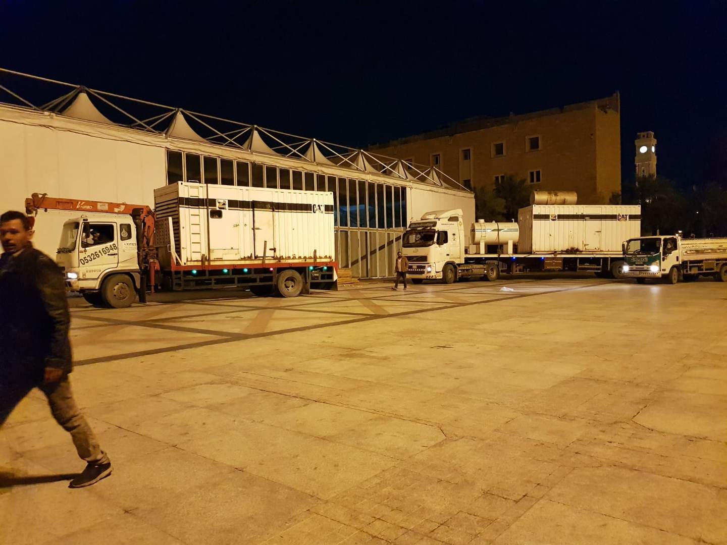 Trucks delivering CAT generator containers to government site at night
